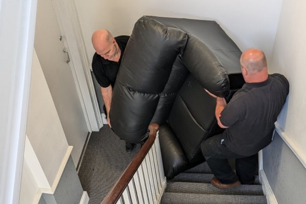 Swansea movers carrying a sofa on a staircase